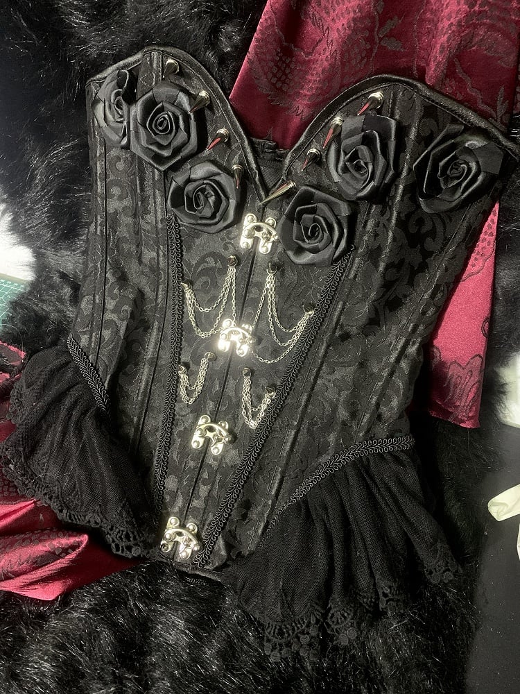 Gothic Korsett mit schwarzen Rosetten und Nieten, verziert mit Kette und Stäbchen