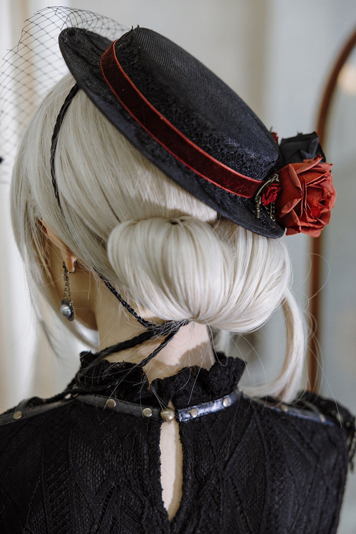 Black veiled hat with red floral trim, rear angle