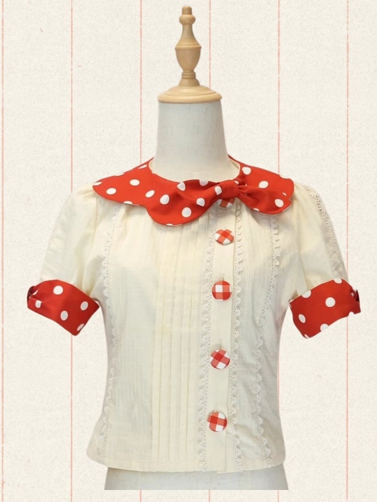 赤い水玉模様の襟と袖口、クリーム色の半袖ブラウス