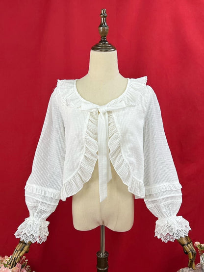 Weißes Oberteil mit Volantbesatz und Knopfleiste, selbstbindendem Ausschnitt und langen Ärmeln
