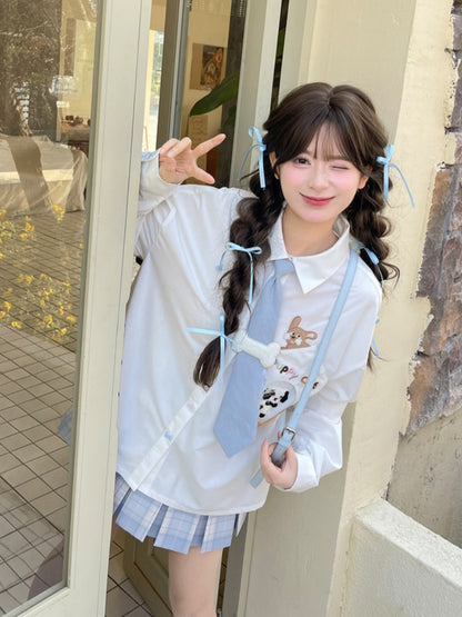 キティの青いネクタイとボーンパピーのアップリケがあしらわれた白いゆったりシャツ