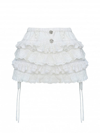Jupe-short argentée ornée de dentelle blanche en forme de rose et de boutons étagés.