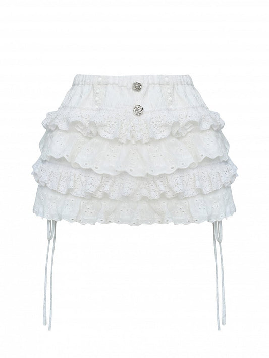 Jupe-short argentée ornée de dentelle blanche en forme de rose et de boutons étagés.