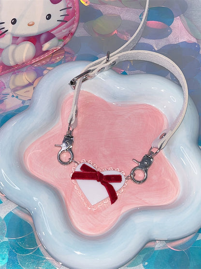 Halsband mit weißem herzförmigem Anhänger und roter Schleife