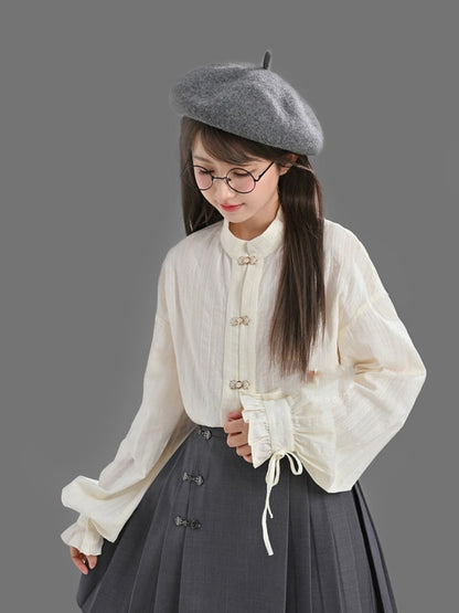 袖口にセルフタイストラップが付いた白いチャイナドレス風シャツ