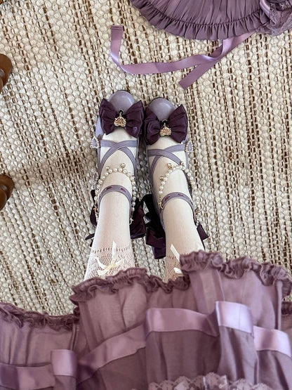 ビーズのハートのクロスデザインのチャームリボン。上部は紫色で装飾されています。