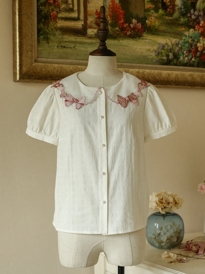 ピンクの蝶結びトリムカラーの白い半袖ブラウス