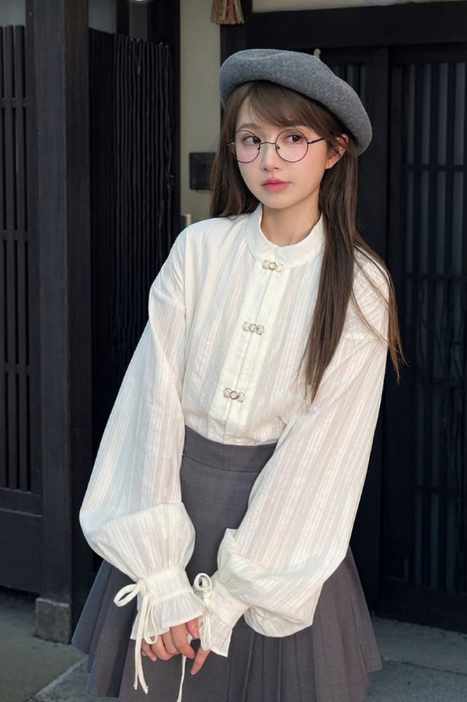 袖口にセルフタイストラップが付いた白いチャイナドレス風シャツ