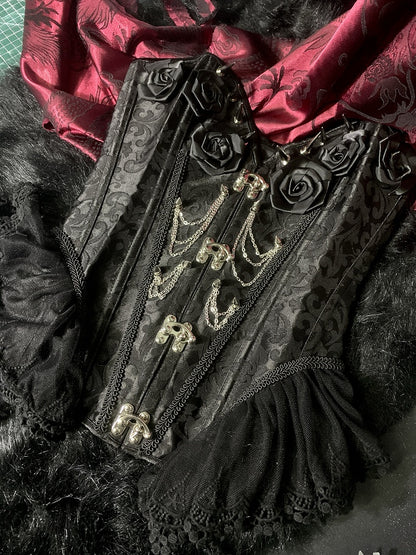 Gothic Korsett mit schwarzen Rosetten und Nieten, verziert mit Kette und Stäbchen