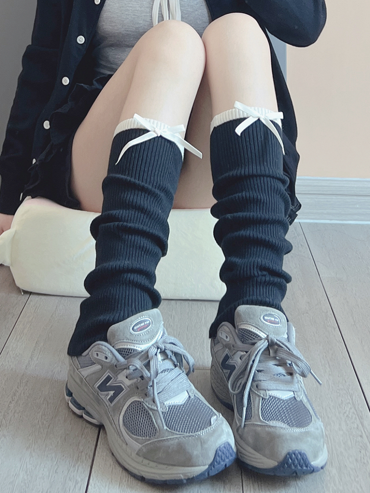 Cremeweiße/schwarze Beinwärmer mit süßer Schleife