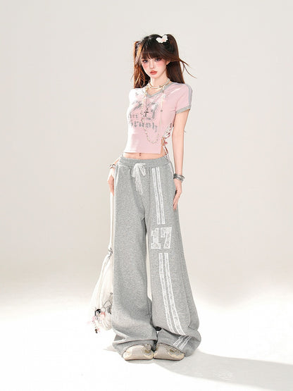 サイドにレースアッププリント、ピンクのVネックにナンバーディテールが入ったグラマラスなクロップドTシャツ