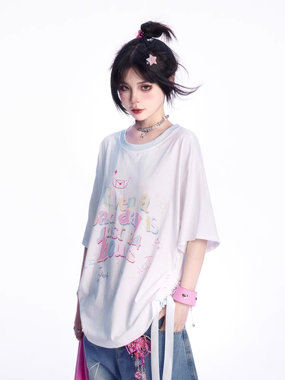 ゆったりとしたTシャツ。裾のディテール。ホワイトのラウンドネック。レタープリント。蝶結び。
