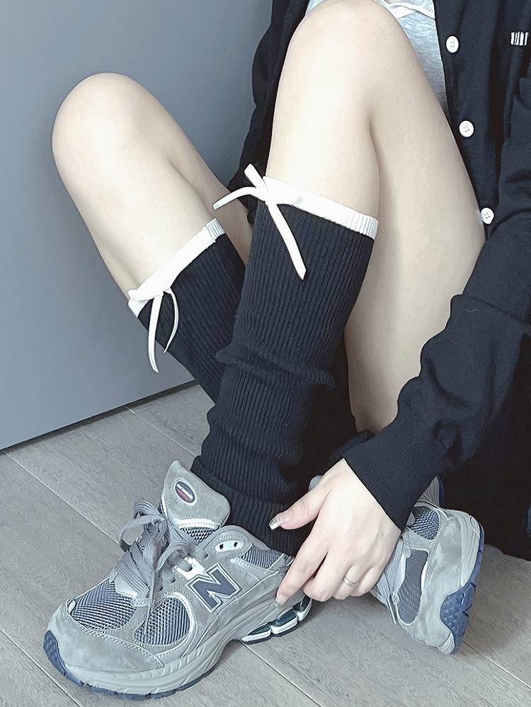 Cremeweiße/schwarze Beinwärmer mit süßer Schleife