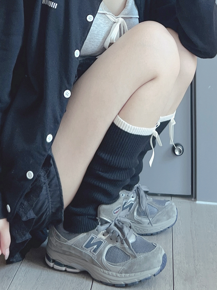 Cremeweiße/schwarze Beinwärmer mit süßer Schleife