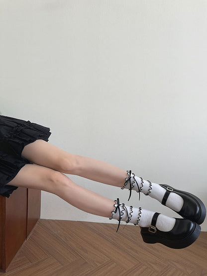 Mit schwarzen Kalbsleder-Socken mit weißen Stufenbesätzen und Schleife und Rüsche