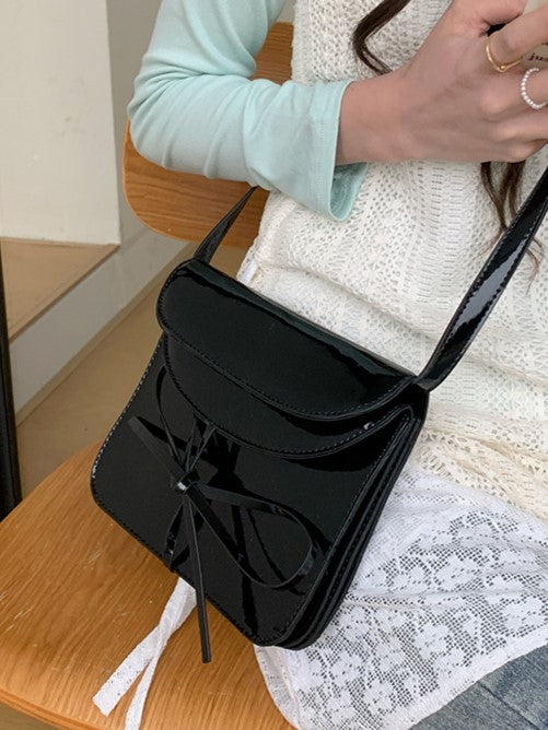 Elegant Black Crossbody Phone Pouch With Glossy Finish And Bow Accent