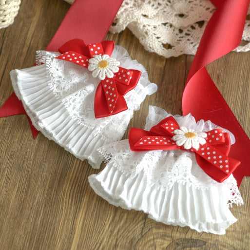 und rote Polka-Akzente am Handgelenk mit weißen, gepunkteten, spitzenbesetzten Schleifen- und Gänseblümchen-Manschetten