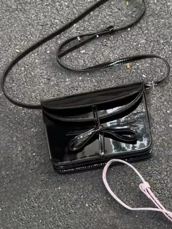 Elegant Black Crossbody Phone Pouch With Glossy Finish And Bow Accent