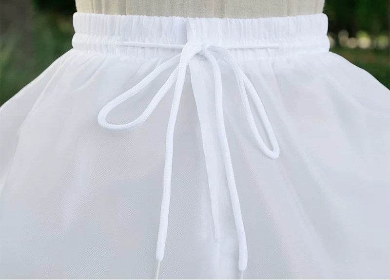 White petticoat with adjustable waistband on a mannequin against a blurred green background.