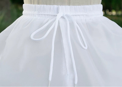 White petticoat with adjustable waistband on a mannequin against a blurred green background.