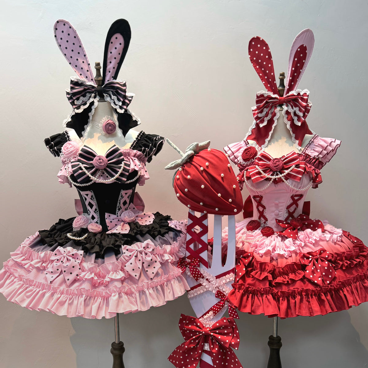 Black and pink dress displayed beside berry red bunny-ear set