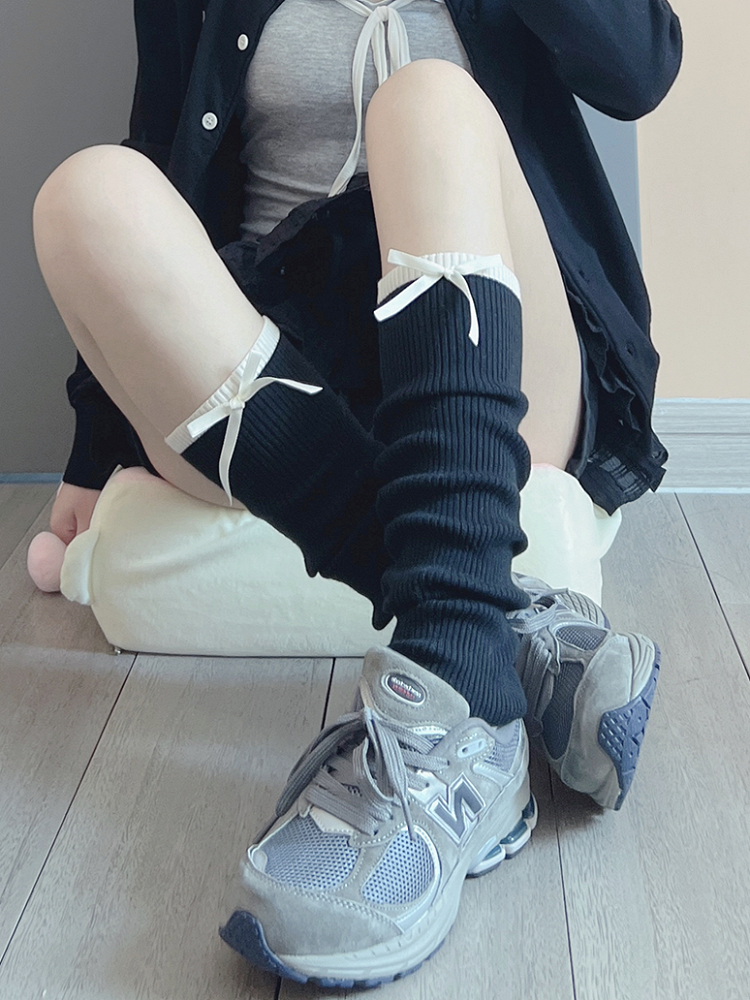 Cremeweiße/schwarze Beinwärmer mit süßer Schleife