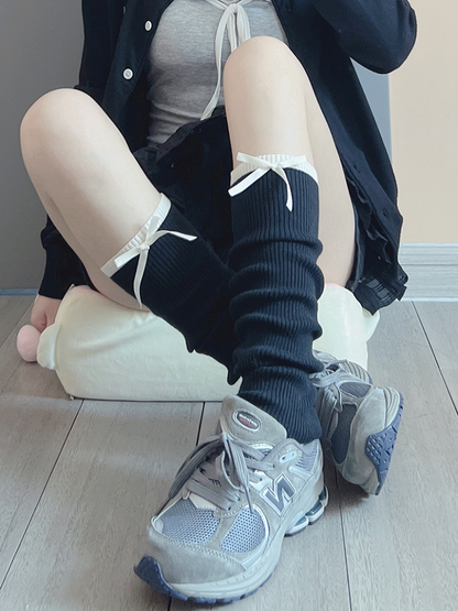 Cremeweiße/schwarze Beinwärmer mit süßer Schleife