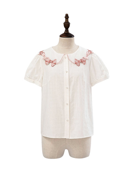 ピンクの蝶結びトリムカラーの白い半袖ブラウス