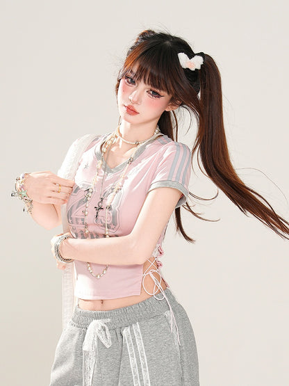 サイドにレースアッププリント、ピンクのVネックにナンバーディテールが入ったグラマラスなクロップドTシャツ