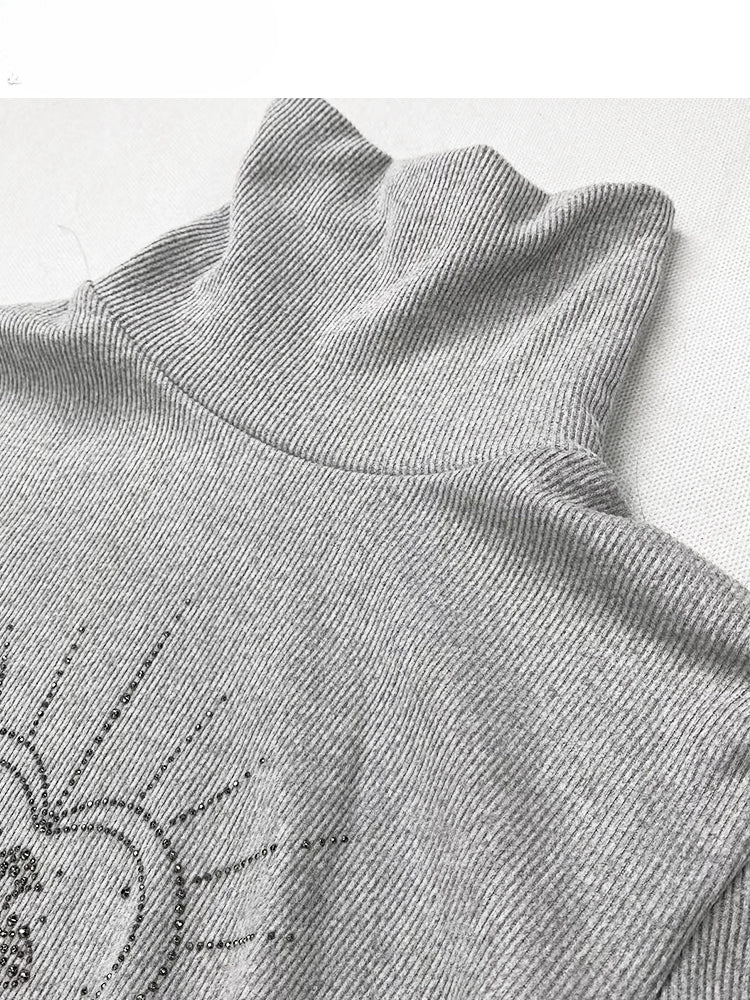 Hellgraues Stricktop mit hohem Halsausschnitt und herzförmigen Strasssteinen