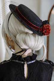 Black veiled hat with red floral trim, rear angle