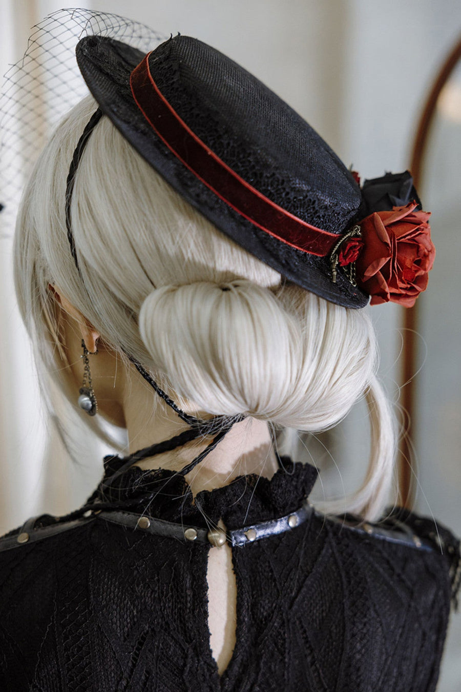Black veiled hat with red floral trim, rear angle
