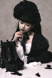 Black platform boots held in Gothic styling