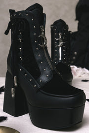 Black ankle boots with laced side panels on a table