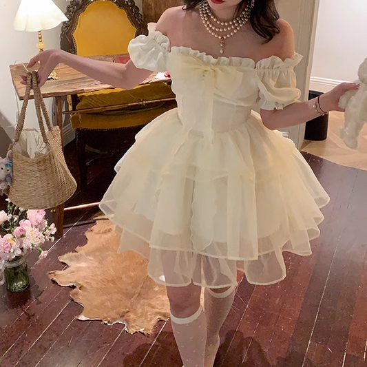 Woman in a white off-shoulder dress with a bow headband in an indoor setting.