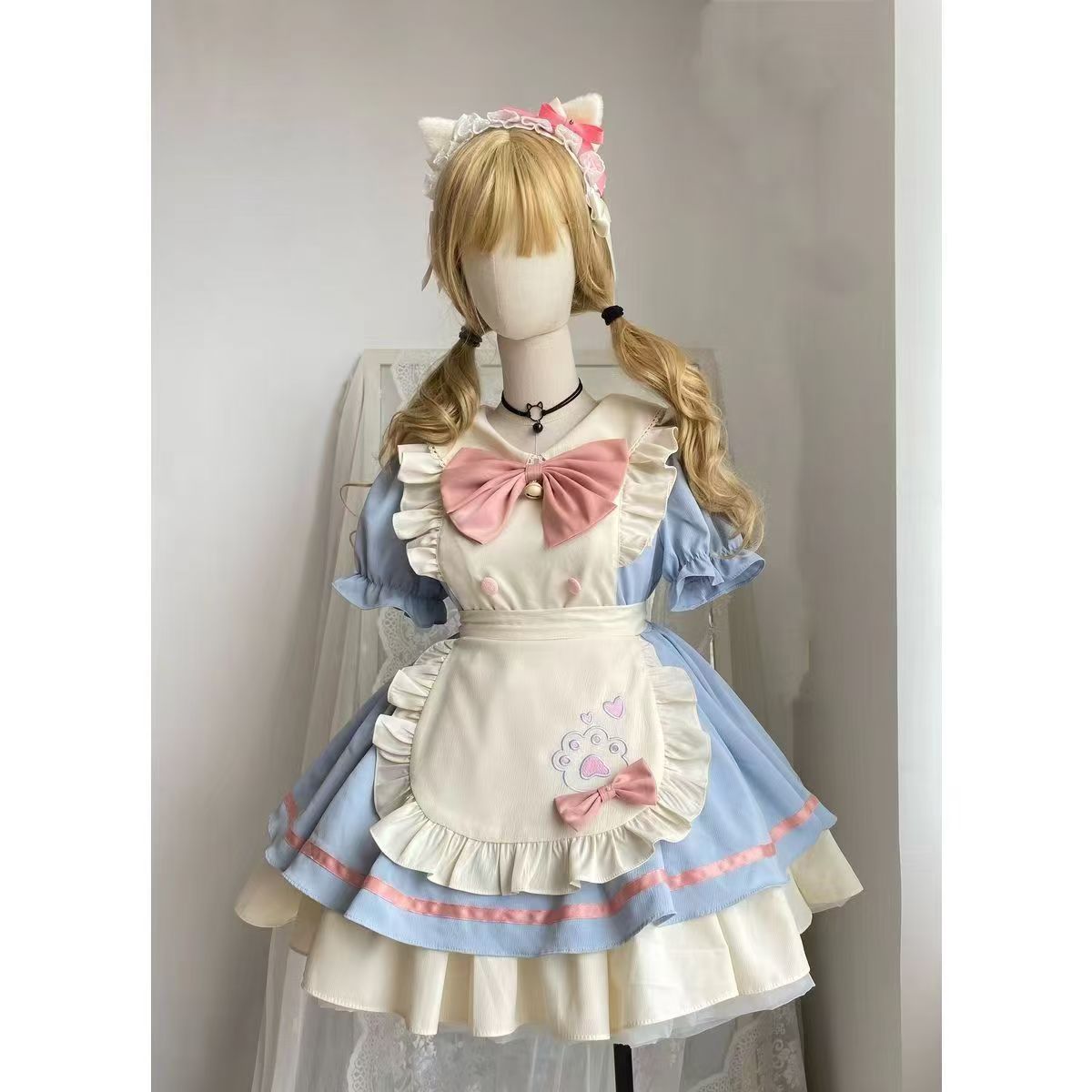 Mannequin wearing a pastel-colored maid outfit with a bow and cat ears against a plain background