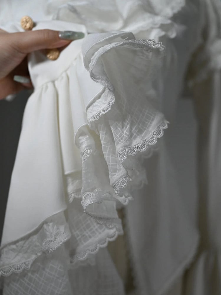 Chemise blanche asymétrique à manches longues, col jabot et ourlet à volants.